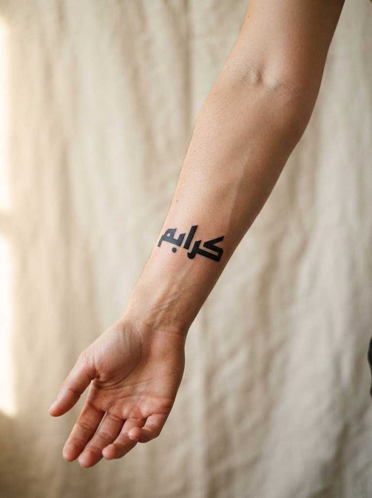 Mubarak (blessed) Arabic tattoo in Kufic calligraphy on forearm